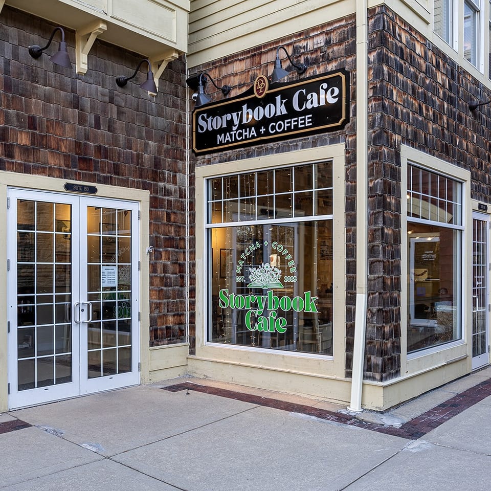 Exterior storefront of Storybook Cafe, a matcha and coffee shop, with shingled walls, large windows, and glass doors.