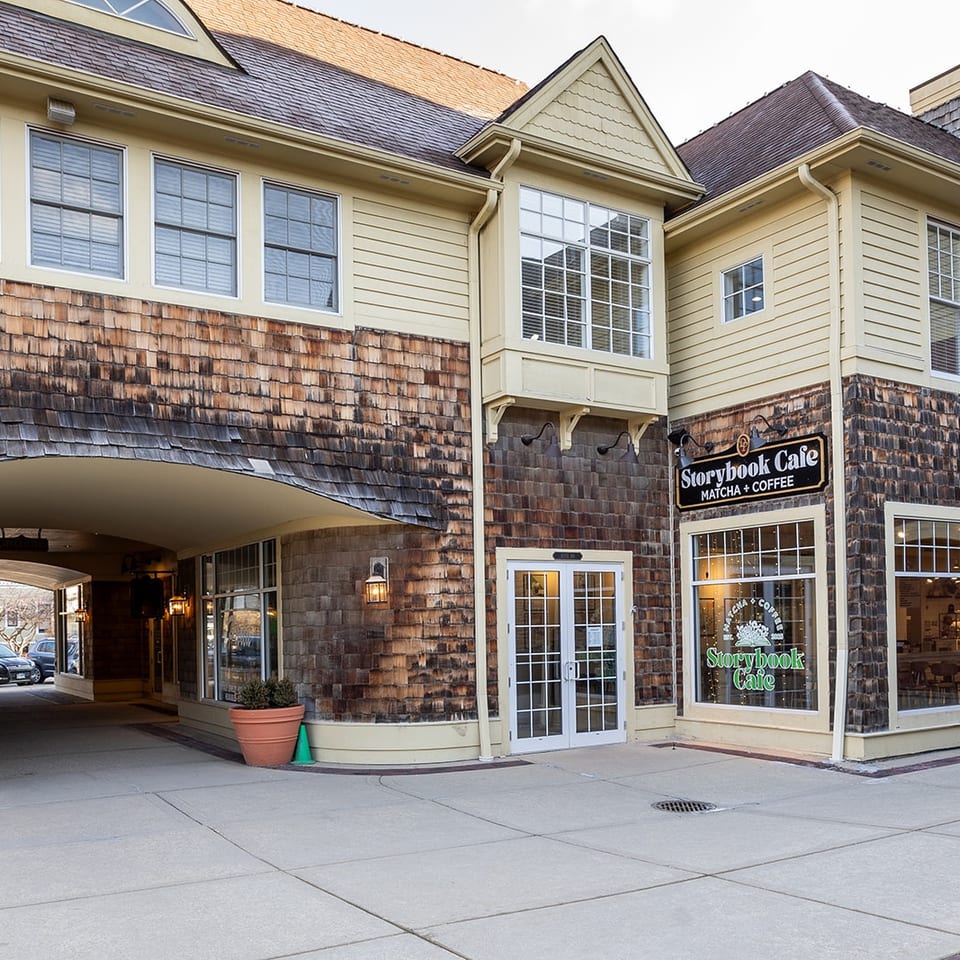 Exterior of Storybook Cafe, featuring shingled walls, large windows, entrance doors, and an arched passageway.